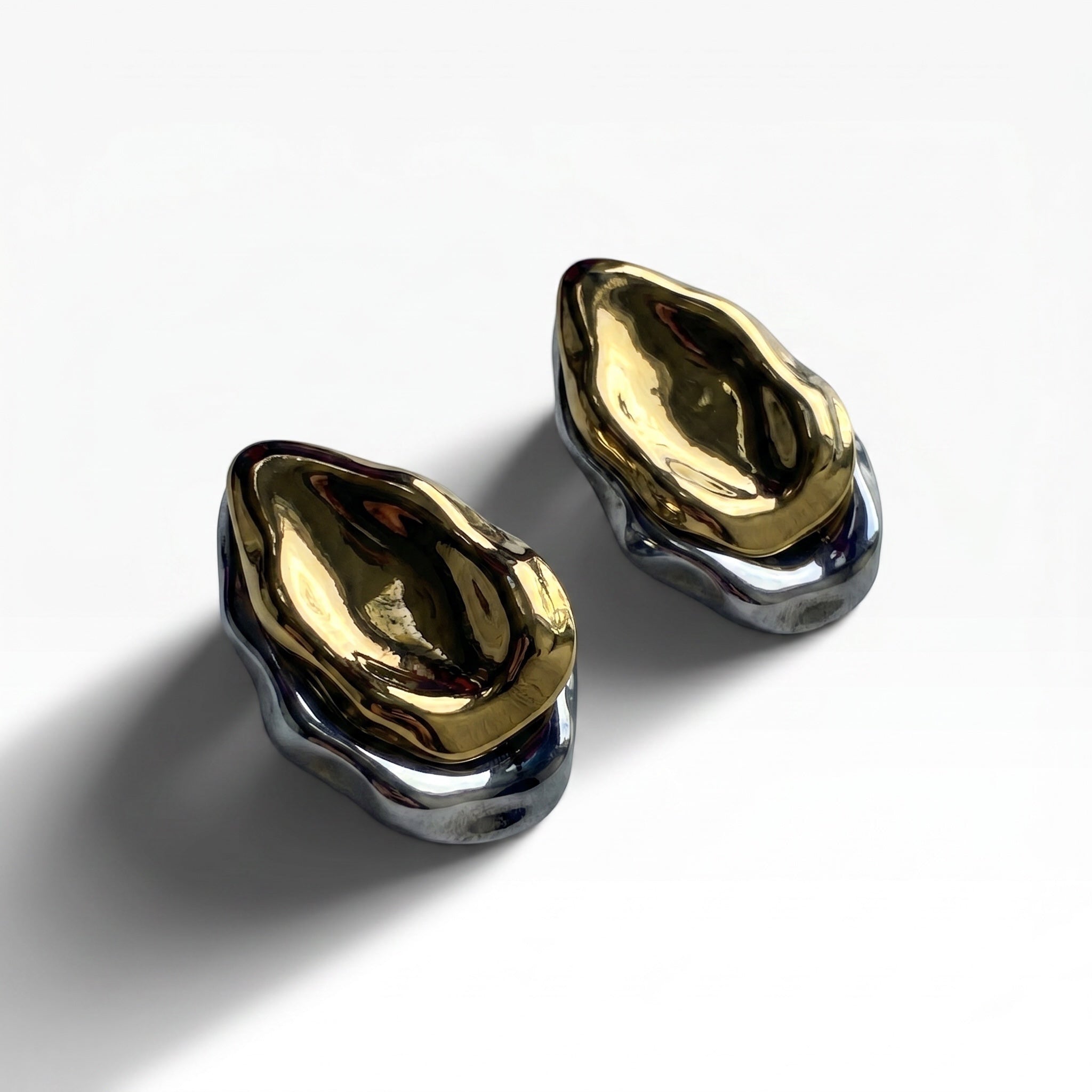 TALI abstract sculptural statement earrings featuring a polished gold center and sleek silver base with organic contours.