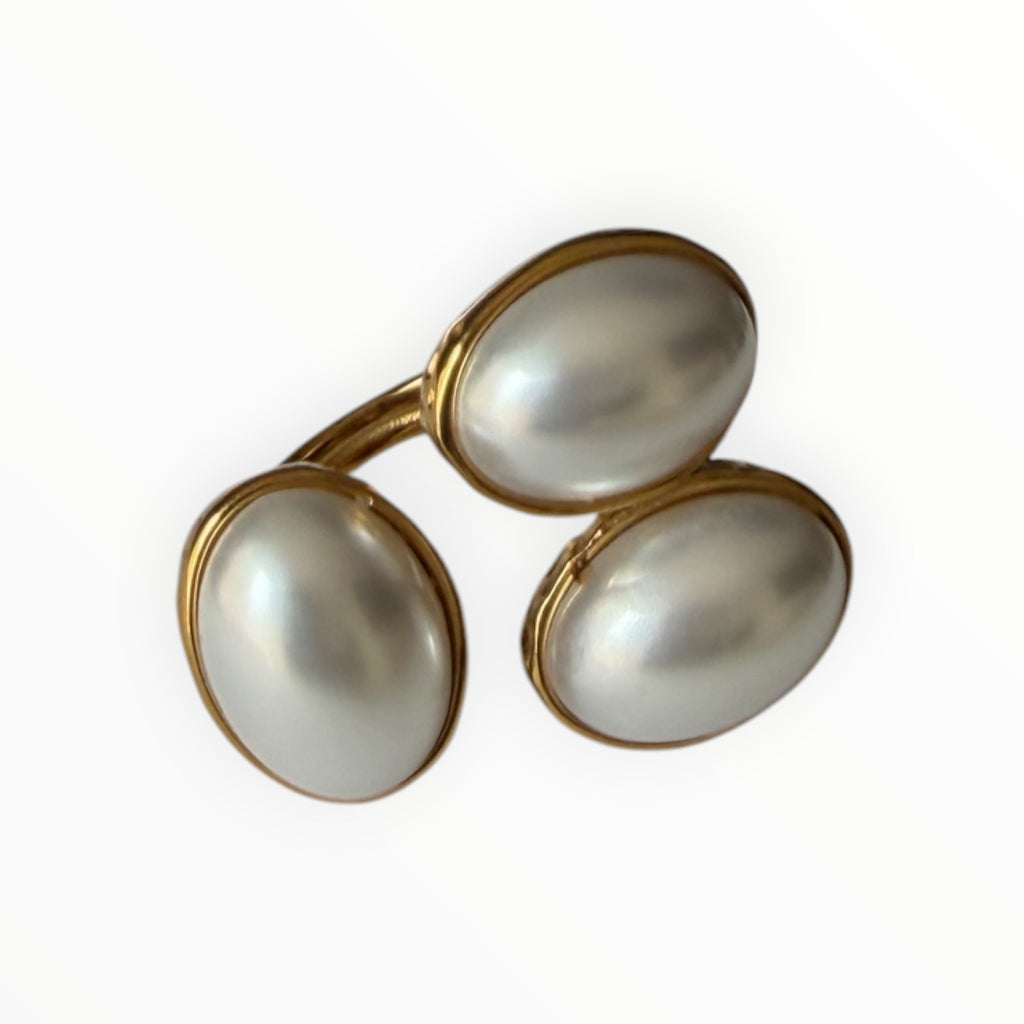 TALI triple oval stone statement ring featuring three white cabochon stones set in a gold-toned hammered metal frame.