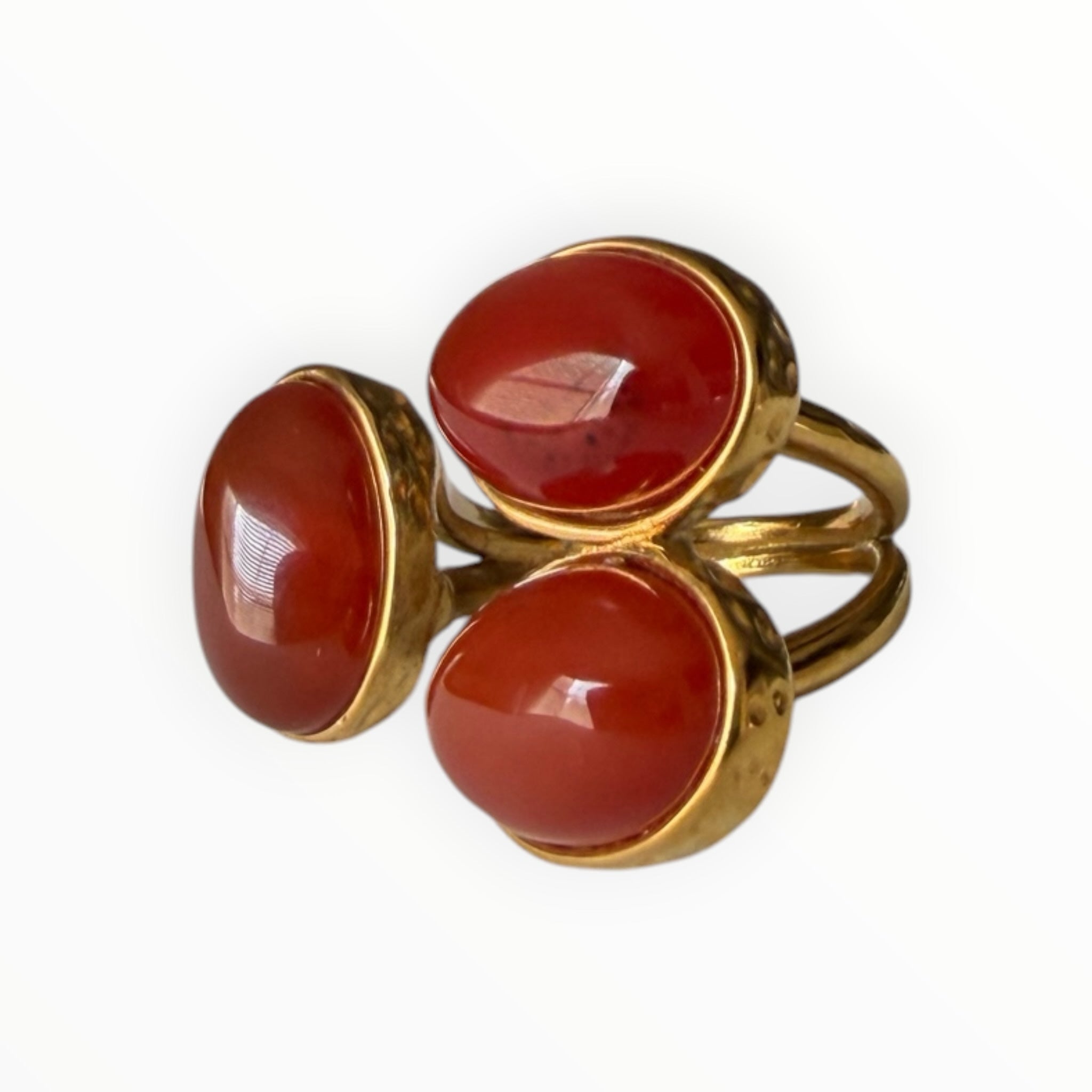 TALI triple oval statement ring featuring three smooth red cabochon stones set in a hammered gold-toned metal frame.