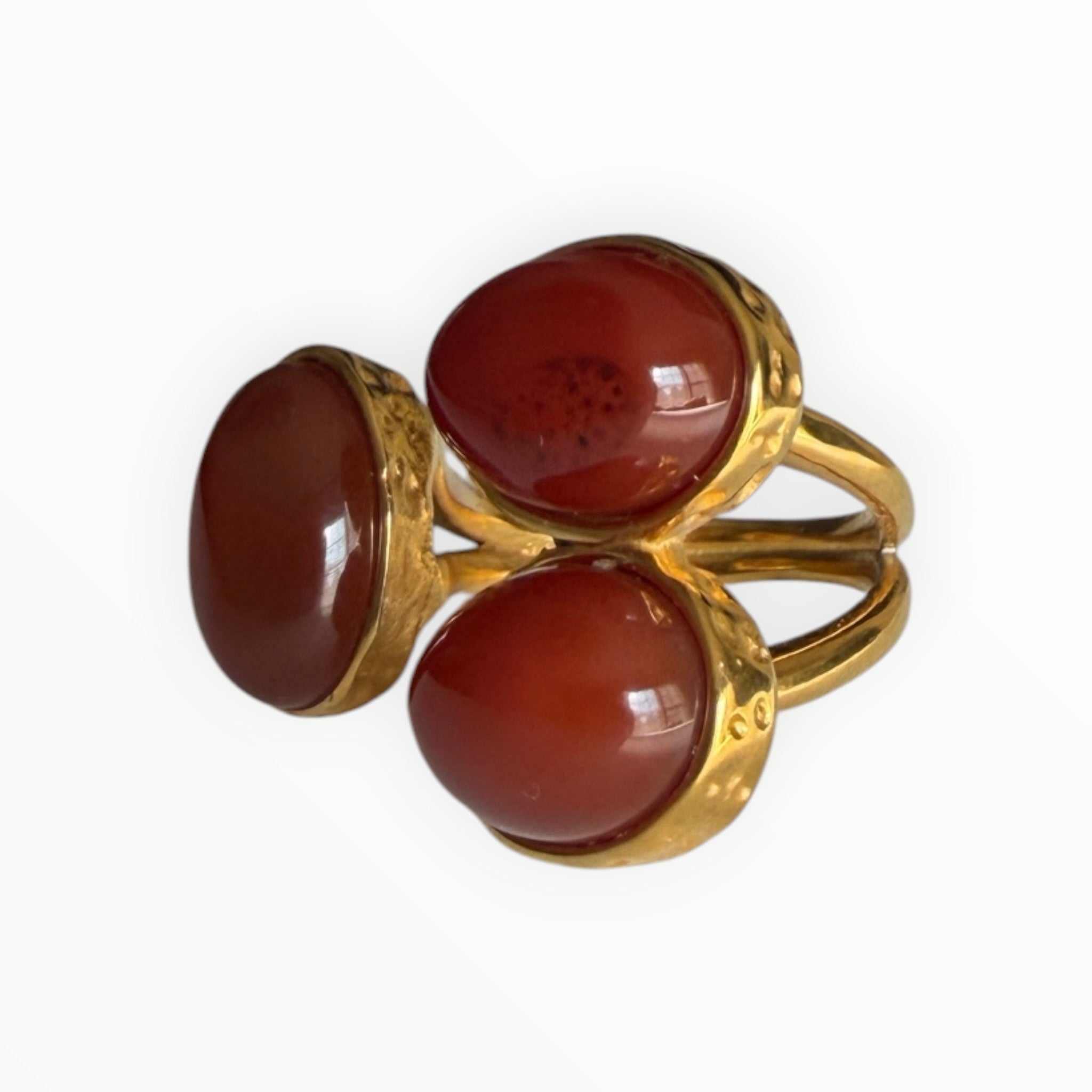 TALI triple oval statement ring featuring three smooth red cabochon stones set in a hammered gold-toned metal band.