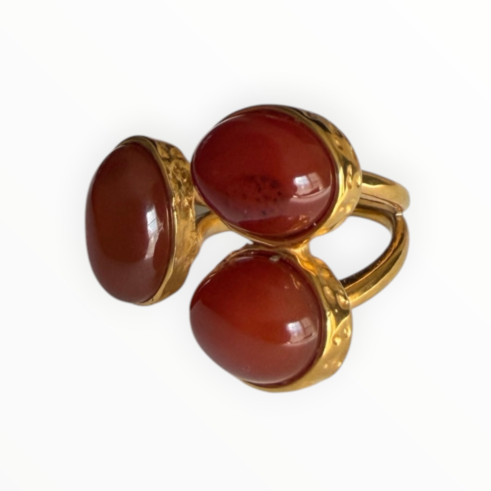 TALI triple oval statement ring featuring three smooth red cabochon stones set in a hammered gold-toned metal frame.